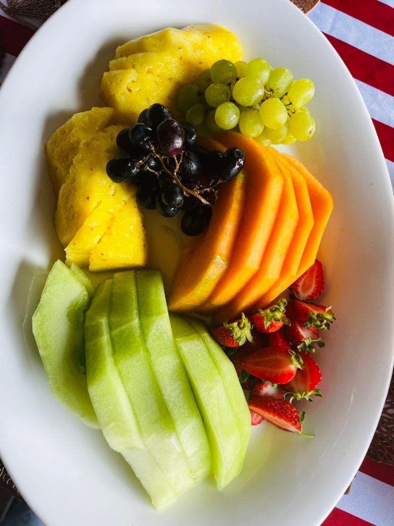 A platter of sliced pineapple, melon, grapes and strawberries